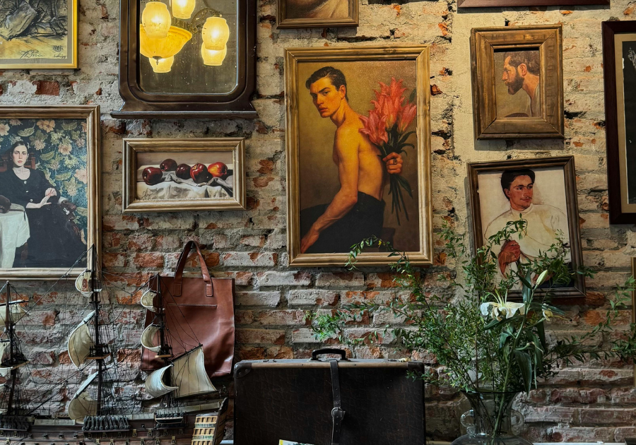 Gallery wall of artwork photos with a suitcase and model ship